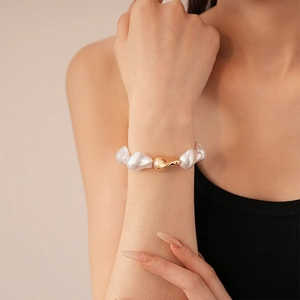 Gros plan sur un bracelet de perles baroques avec boucle en métal doré au poignet