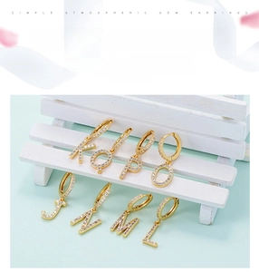 Detailed close-up of zircon-encrusted alphabet pendant earrings in a golden finish