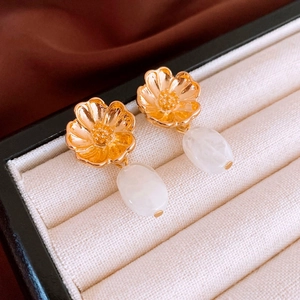 Detail of vintage golden flower earrings with white resin drops on velvet jewelry box