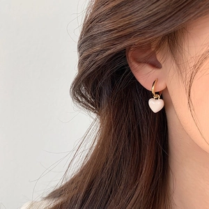 Boucles d'oreilles cœur rose avec créoles dorées sur un modèle pour un look élégant