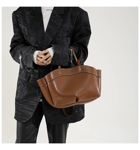 Dettaglio della borsa tote in pelle marrone caramello con cuciture bianche e modella