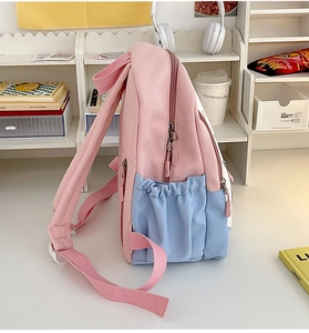 Side view of pink and blue contrast backpack on a desk with lifestyle school accessories