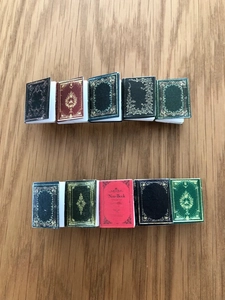 Close-up of ten vintage miniature model books in red, green and black on a wood surface