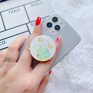 Close-up of galaxy star planet phone grip with glitter and epoxy finish held in hand