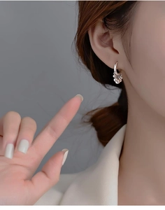 Detailed view of silver hoop earrings with delicate metal bead fringe on a female model