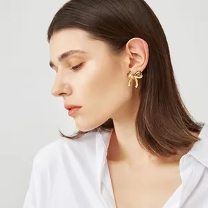 Elegant gold ribbon bow stud earrings for women shown on a model in a minimalist style