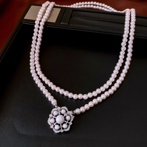 Detail view of double-layer white pearl necklace with an ornate floral rhinestone clasp