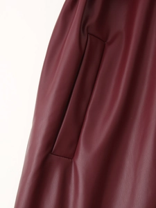 Détail de la texture en cuir PU rouge foncé et poche latérale inclinée sur le manteau long
