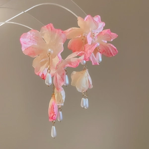 Detail of pink fabric flower earrings with faux pearl tassels and gold metal chain links