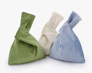 Detailed view of colorful velvet knot wrist bags in green, beige and light blue tones