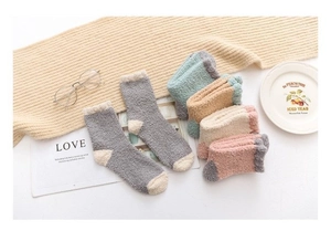 Flat lay of colorful thick coral fleece socks with cozy winter home accessories