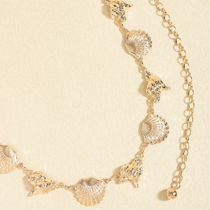 Detail of vintage gold metal waist chain featuring starfish and shell charms for beach wear