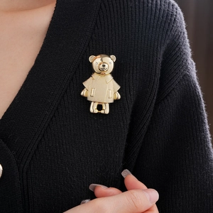 Detail einer goldfarbenen Bärenbrosche mit Strasssteinen auf einer schwarzen Strickjacke
