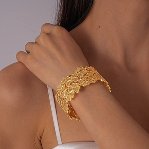 Détail macro du bracelet manchette doré avec motifs floraux ajourés et style bohème chic