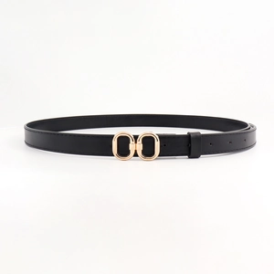 Détail d'une ceinture fine en cuir noir avec une boucle à double anneau en métal doré