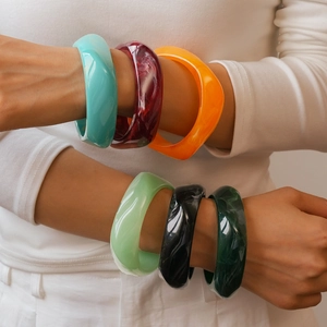 Close-up of vibrant resin swirl bangles on a model's wrist with marbled texture