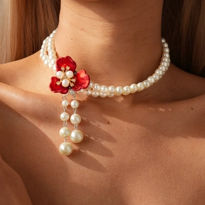 Close-up of double-layer pearl necklace with red enamel flower and tassel pendant