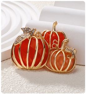 Close-up of elegant pumpkin brooch with orange rhinestones and gold-tone metal finish