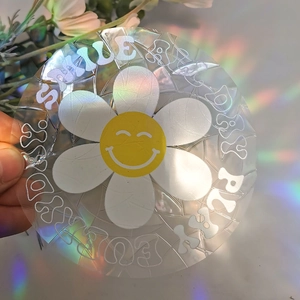 Macro shot of suncatcher window decal featuring a white daisy and rainbow light effect