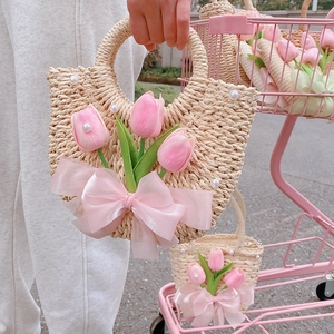 Detail of straw handbag with pink tulips, satin bow and white pearl accents