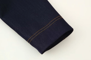 Détail macro du tissu sergé bleu foncé avec coutures contrastées orange sur la veste