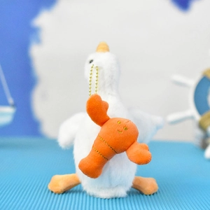 Detailed macro shot of a cute plush white goose holding a small orange lobster charm