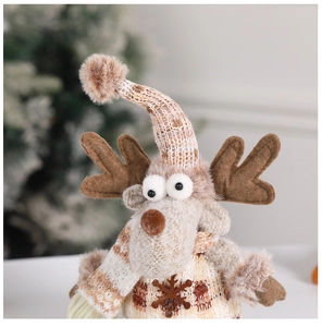 Close-up of plush Christmas reindeer ornament with knitted scarf and snowflake detail