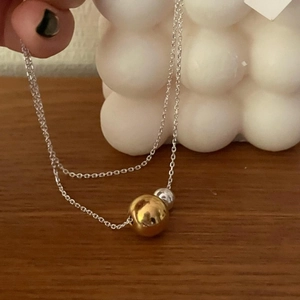 Detailed view of minimalist double bead pendant necklace with gold and silver spheres
