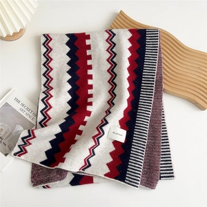 Close-up of tricolor knitted scarf with geometric patterns and branded woven label