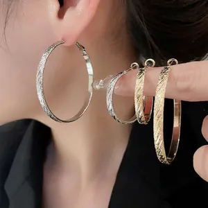 Elegant textured gold and silver hoop earrings in various sizes shown on a model