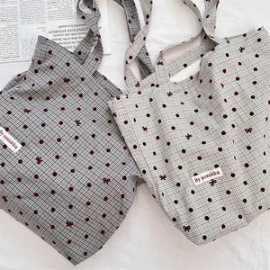 Detail of canvas tote bags with polka dots and bow patterns in dark gray and light green