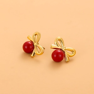 Détail de boucles d'oreilles nœud dorées à l'or 18 carats avec perles rouges