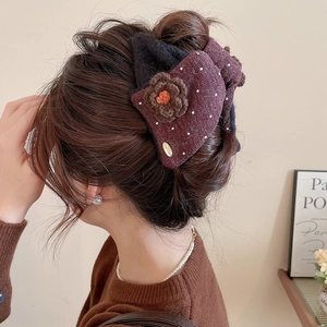 Detail of burgundy plush flower hair claw clip with cozy knitted texture on brown hair