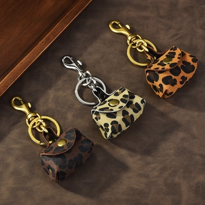 Three vintage leopard print mini coin purses with metal keychains on leather background