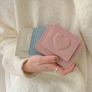 Three macaron-colored PU leather mini wallets with heart stitching held by a model