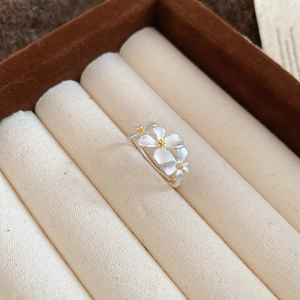 Detail view of matte silver daisy ring with yellow stamens on beige fabric texture