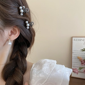 Detail shot of mini pearl hair clips and saturn-style earrings on model for elegant styling