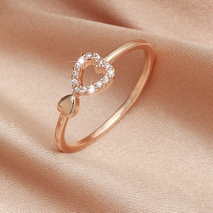 Detail of rose gold heart ring with white zircons on a luxury champagne satin background