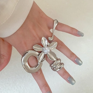 Detailed close-up of a silver floral statement ring with pearl accent and mirror finish