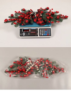 Christmas berry swag detail with red ornaments and a buffalo plaid bow in packaging