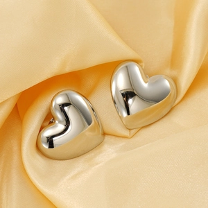 Polished silver 3D heart stud earrings on elegant champagne satin fabric background