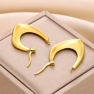 Golden geometric hollow stainless steel hoop earrings on a light brown jewelry box