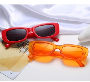 Detail shot of vintage rectangular sunglasses in red and orange on marble and silk