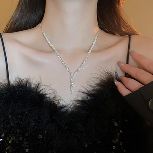 Close-up of elegant Y-shaped silver necklace with zircon tassels worn by a model