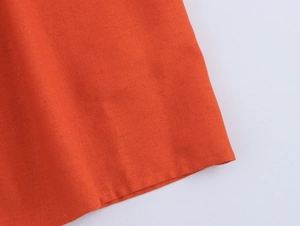 Macro detail of the orange woven fabric texture and stitching on the dress hem
