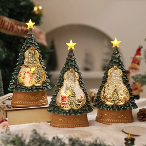 Close-up of lighted Christmas tree music box with swirling snow and Santa figurines