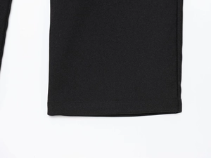 Detailed close-up of black wide-leg trousers showing the premium twill fabric and hem stitching