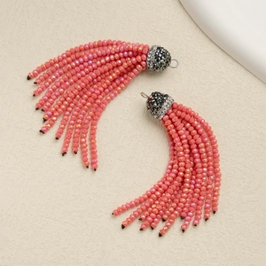 Detail of coral pink beaded tassel earrings with crystal-encrusted dark grey metal caps