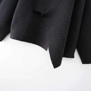 Black knitted poncho with scarf, close-up of side slit detail and textured wool blend fabric