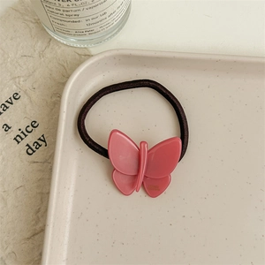 Detail view of a pink resin butterfly hair tie placed on a decorative tray